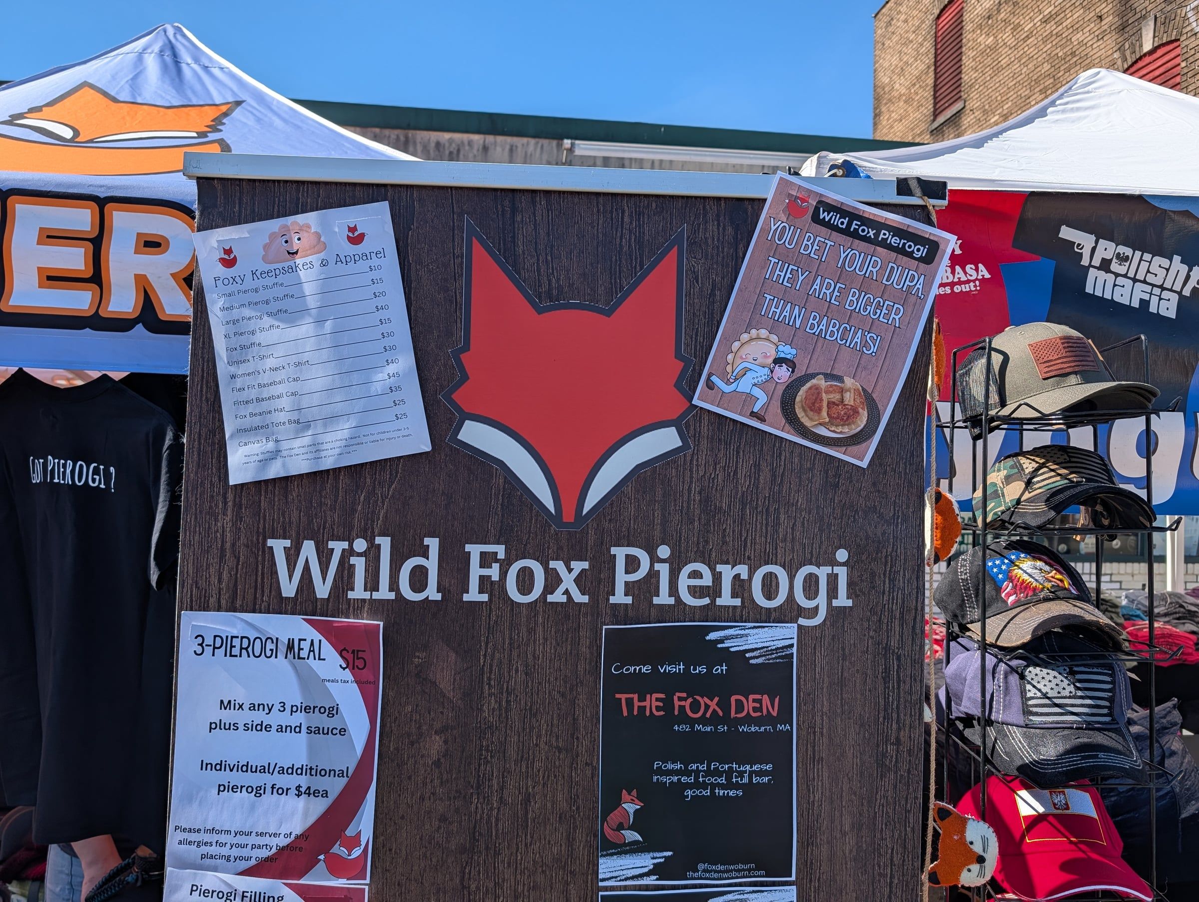 The Wild Fox Pierogi sign at a market, with the pierogi menu and a flyer for The Fox Den