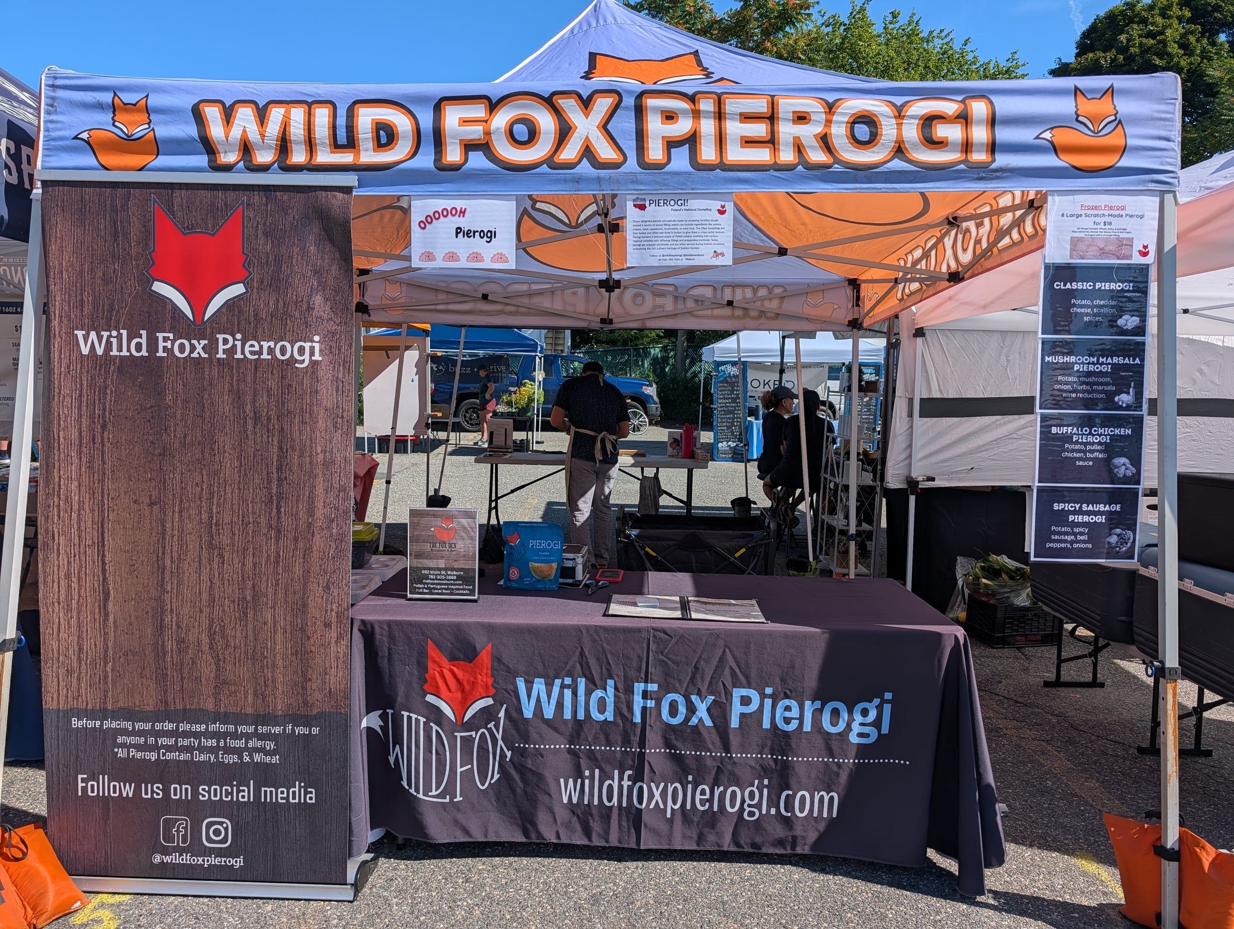 The Wild Fox Pierogi tent at a farmers market, with the flavor menu posted beside it