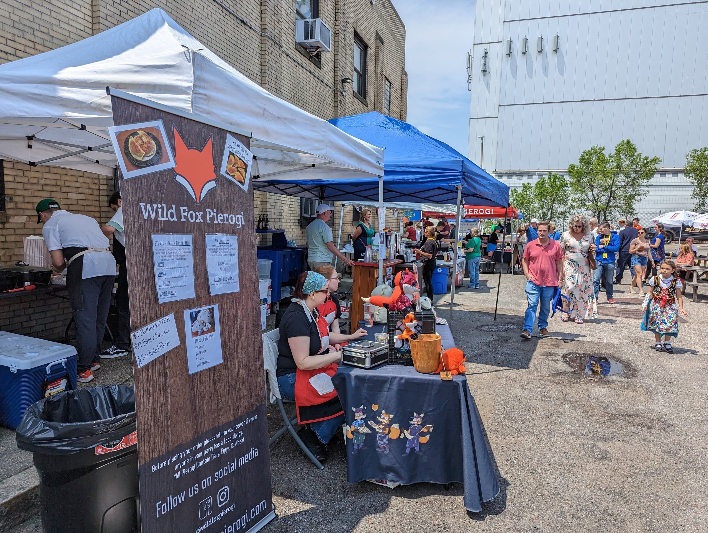 The Wild Fox Pierogi stand at a busy street festival, with a crowd walking past